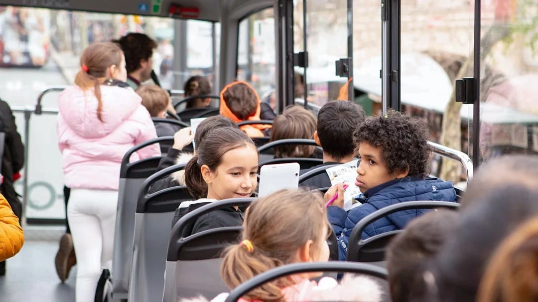 Children enjoying a Tootbus tour in Paris, looking at maps and tablets.