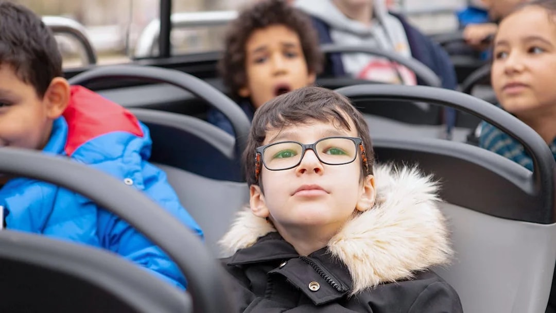 Child with glasses enjoying view on Tootbus tour in Paris.