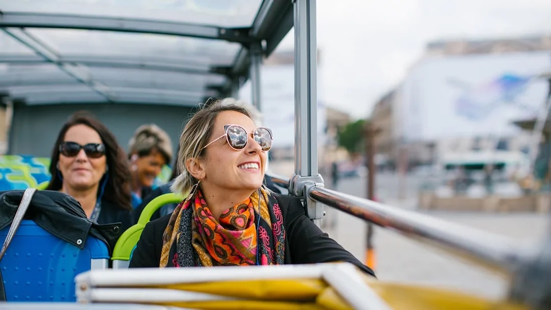 Woman enjoying a hop-on hop-off bus tour in Paris.