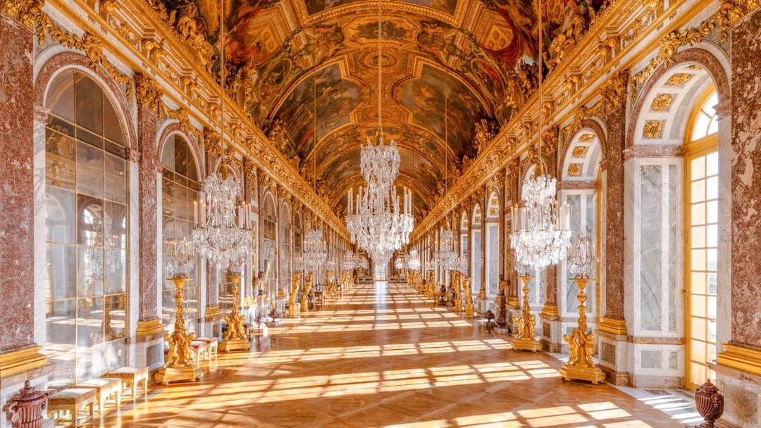 Gallery of Mirrors in Versailles Palace, Paris, showcasing ornate chandeliers and reflective mirrors.