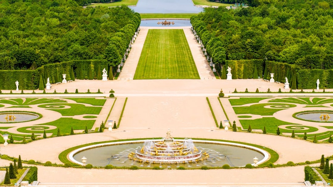 Fountain and gardens at Versailles Palace, Paris, with manicured lawns and statues.