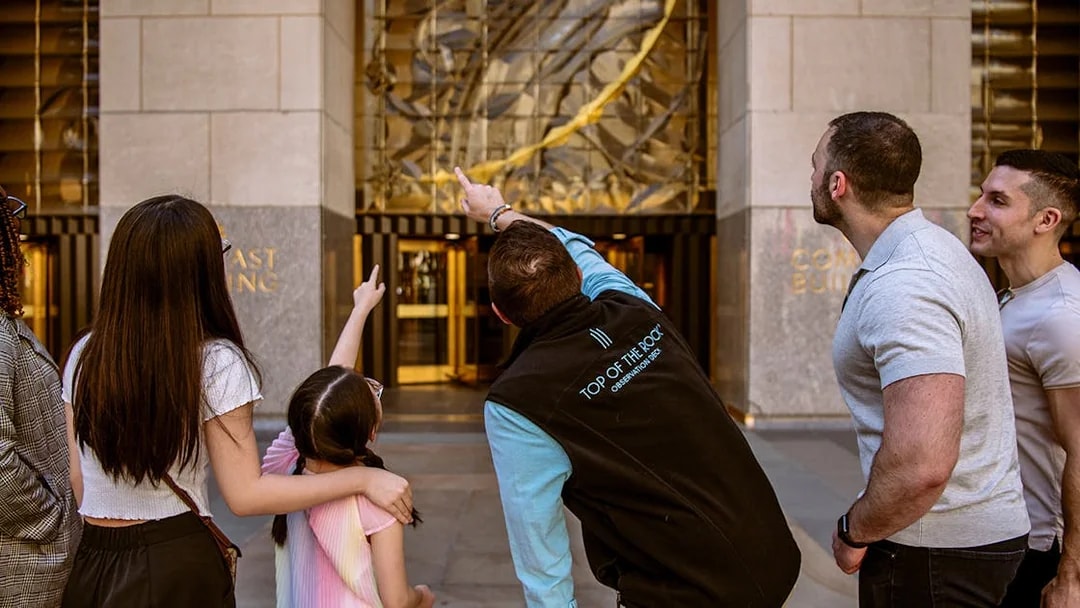 Visitors pointing at the entrance of Top of the Rock Observation Deck in New York City.