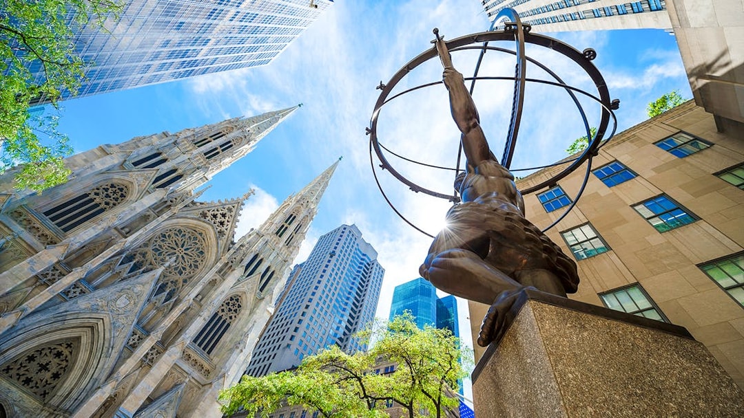 Atlas statue at Rockefeller Center with St. Patrick's Cathedral and skyscrapers in New York City.