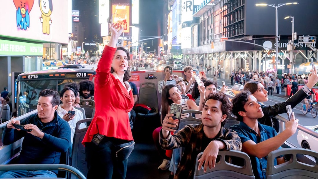 Tour guide speaking to tourists on a New York Hop On Hop Off bus in Times Square.