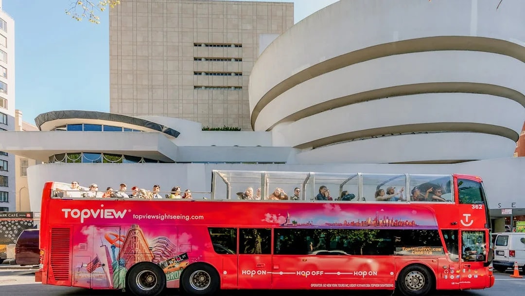 Red double-decker tour bus in front of the Guggenheim Museum, New York City.