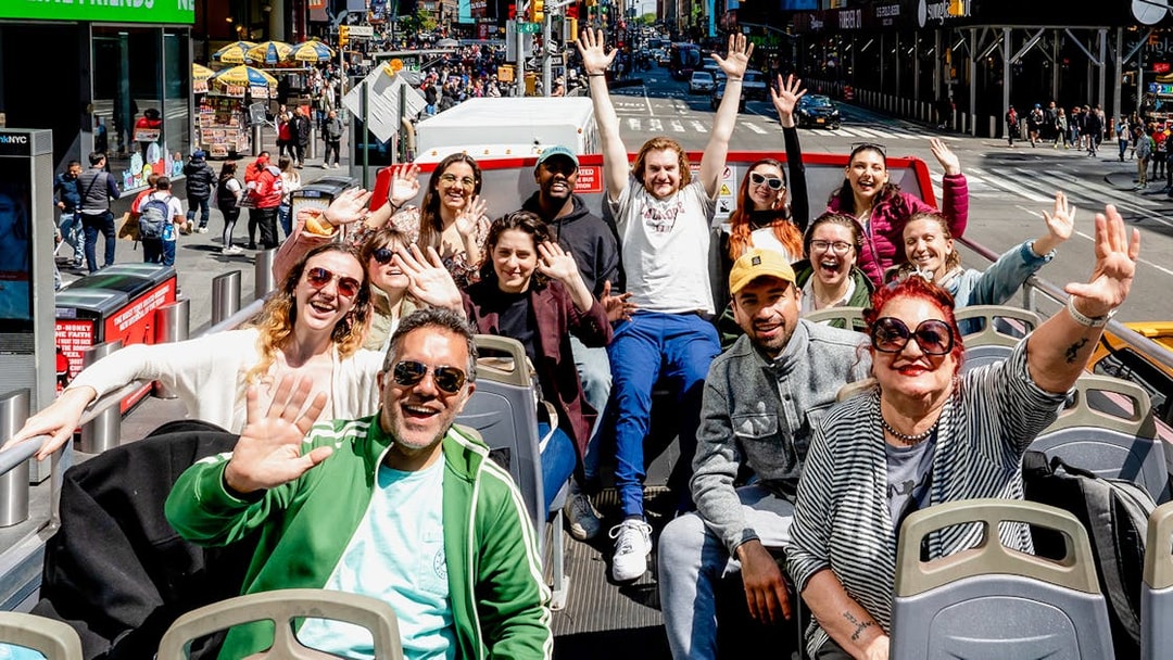 People waving on a New York Hop On Hop Off bus tour.