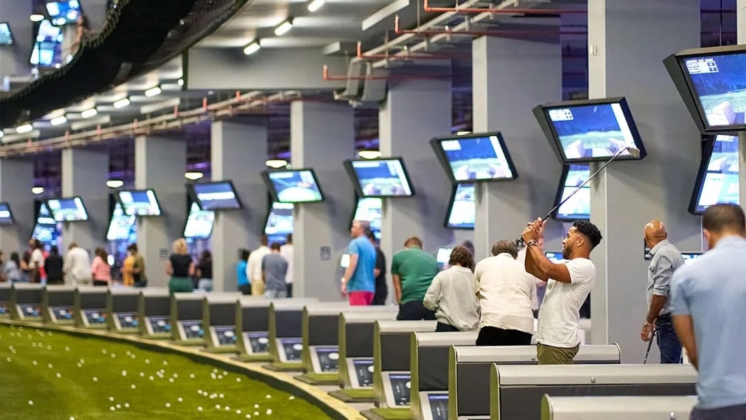 Golfers playing at Topgolf Dubai with multiple screens and targets in view.