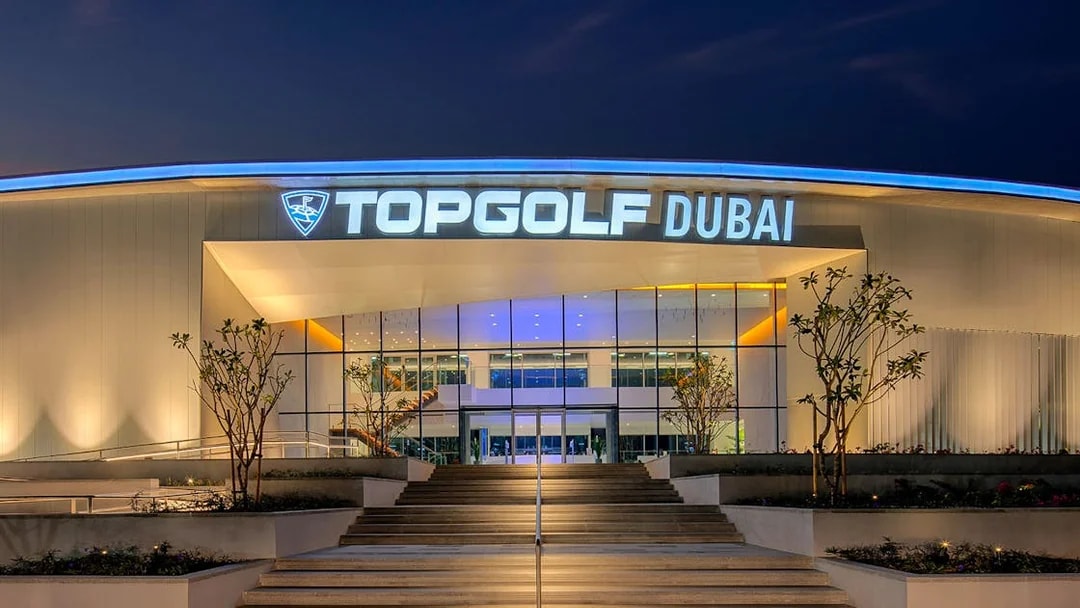 Topgolf Dubai entrance illuminated at night, showcasing modern architecture.