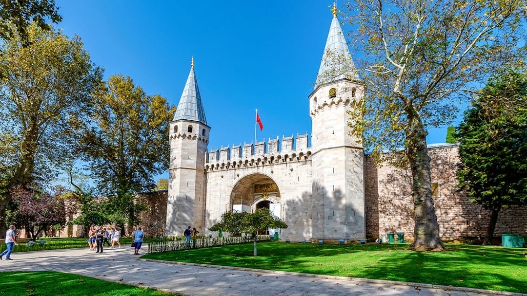 Gate of Salutation at Topkapi Palace, Istanbul, with visitors walking nearby.