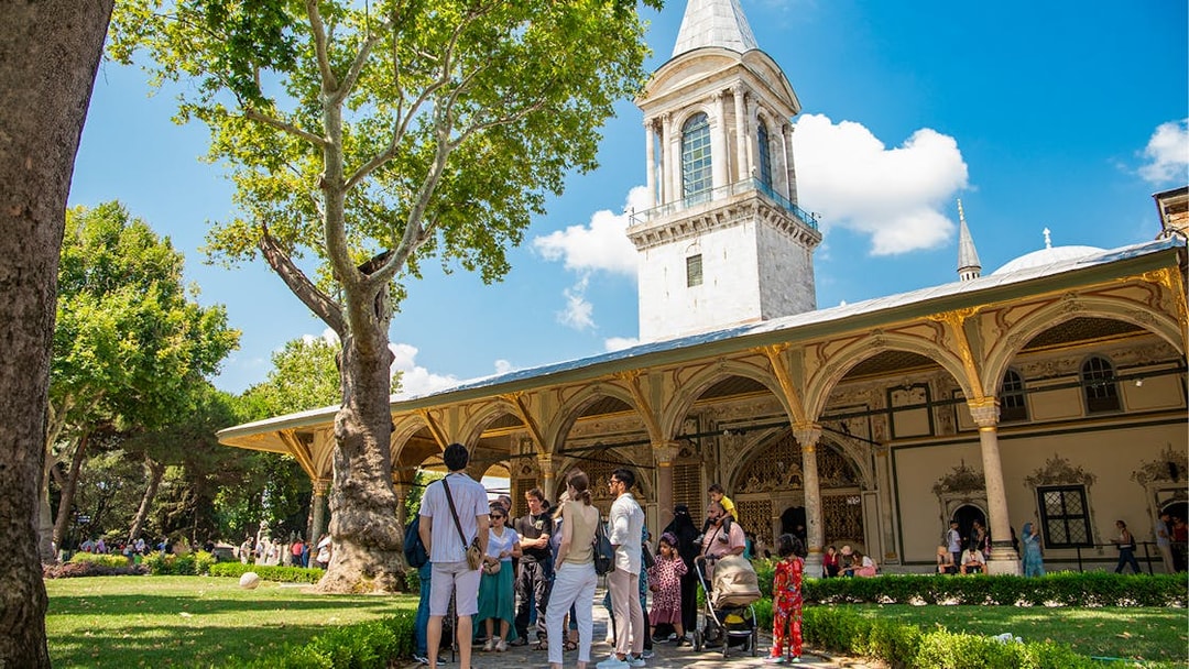 Tour group exploring Topkapi Palace courtyard in Istanbul.