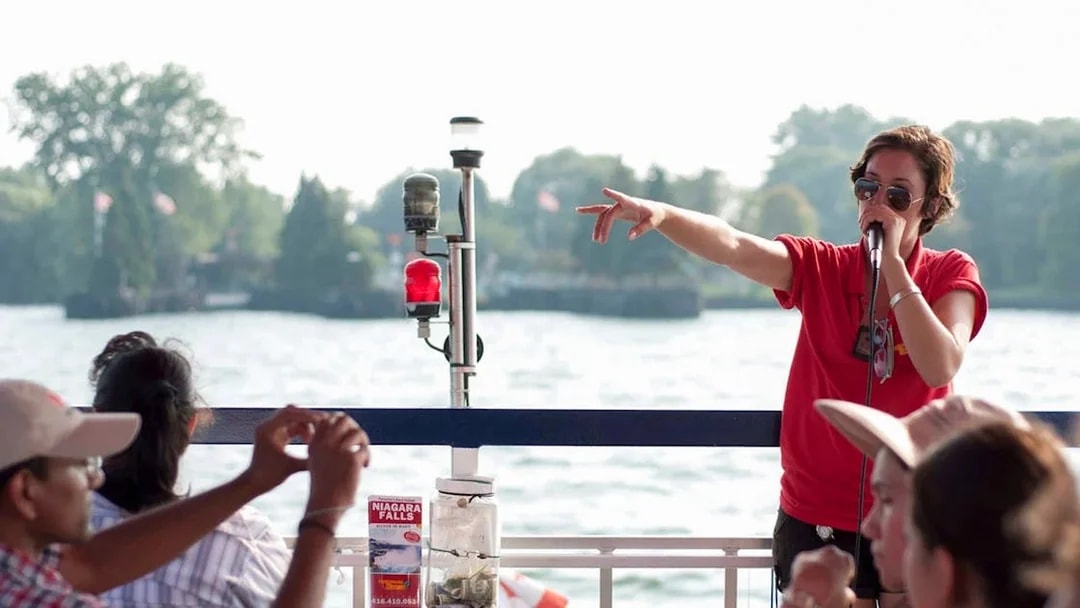 Tour guide speaking to passengers on a Toronto Harbour cruise with islands in the background.