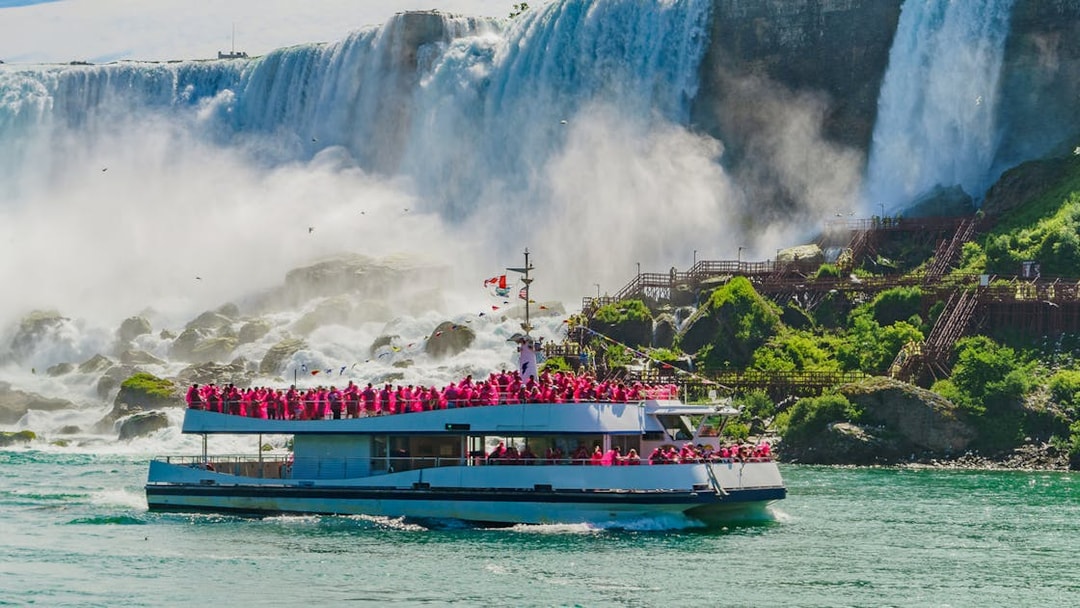 Boat cruise approaching Niagara Falls with passengers in pink raincoats.