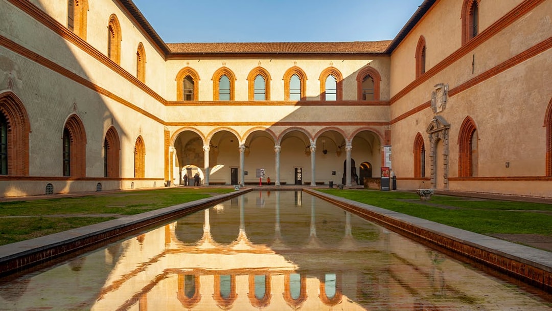 Sforza Castle courtyard with arched walkways and reflective pool, Milan, Italy.
