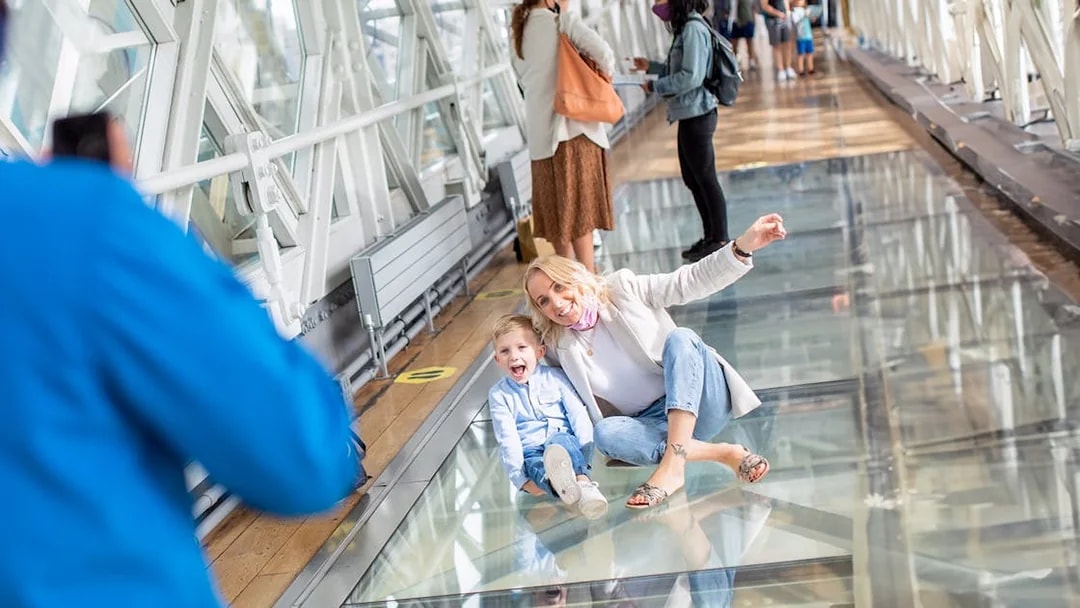Visitors enjoying the glass walkway at Tower Bridge, London.