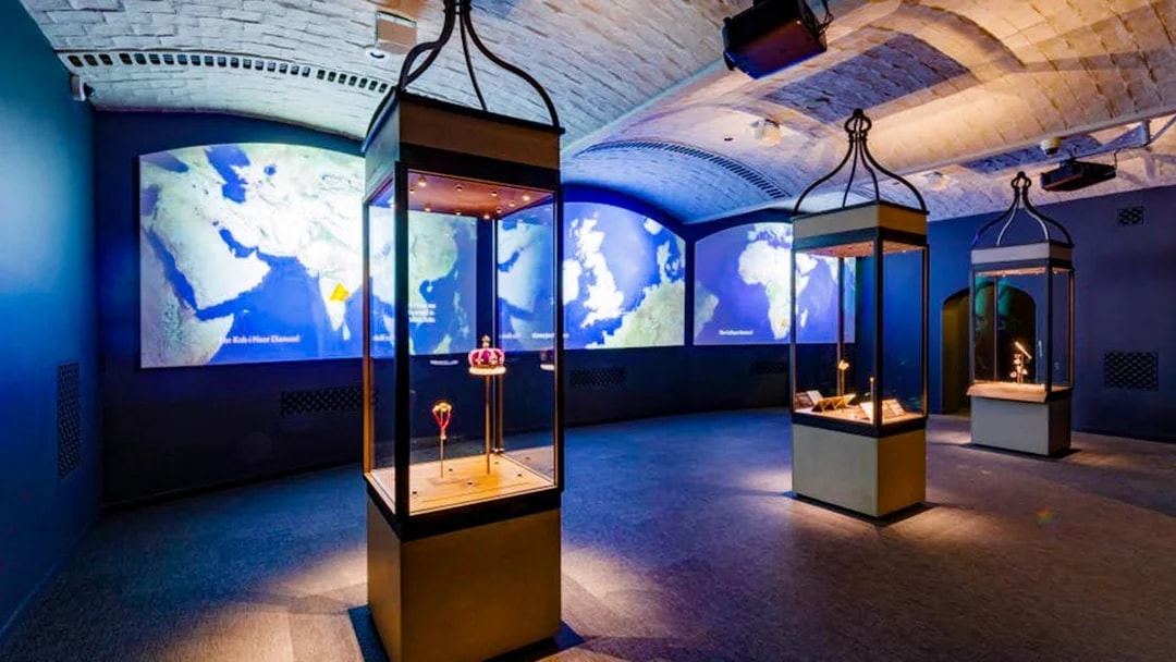 Exhibit room with illuminated display cases and world maps at Historic Royal Palaces.