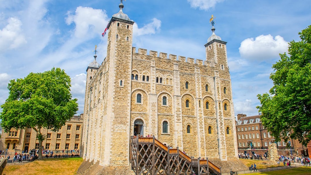 White Tower at the Tower of London with tourists exploring the historic site.