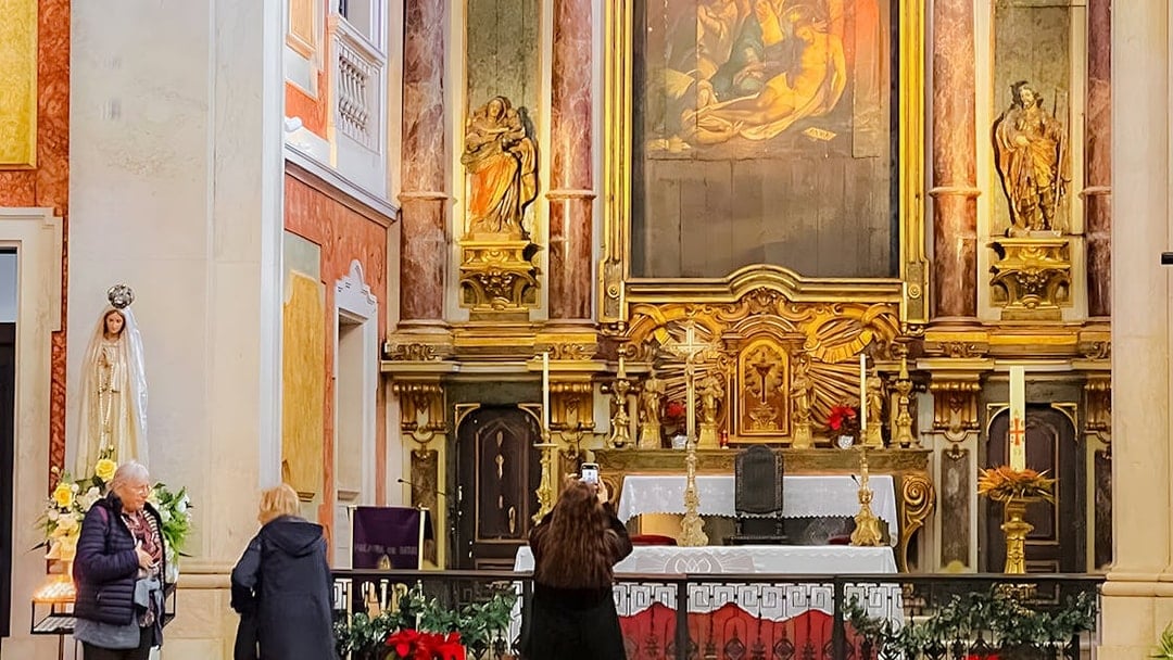 Altar inside St George's Castle Church with visitors and religious statues.