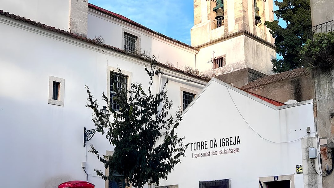 Tower of St. George's Castle Church in Lisbon with bell tower and white facade.