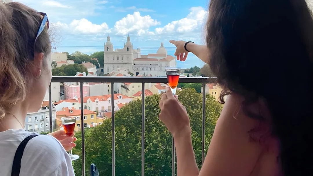 Women enjoying drinks with a view of São Jorge Castle Church in Lisbon.