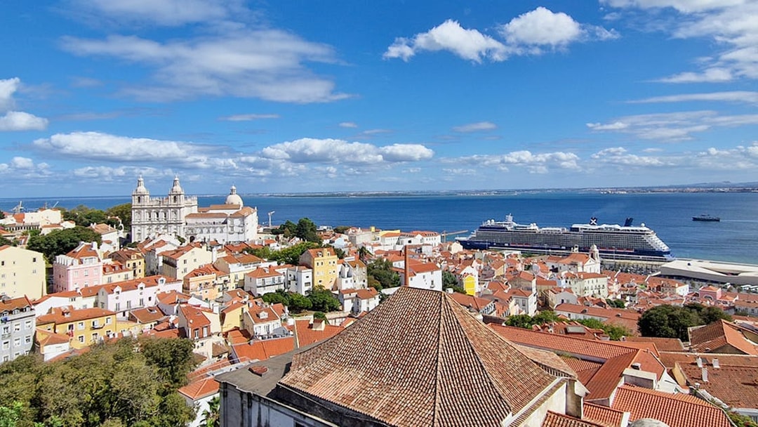 Lisbon cityscape with St. George's Castle Church tower and cruise ship in the harbor.
