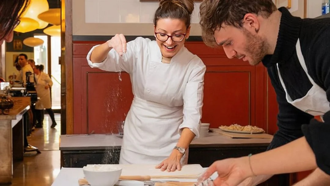 Preparing pasta at a cooking class in Rome, with participants learning techniques.