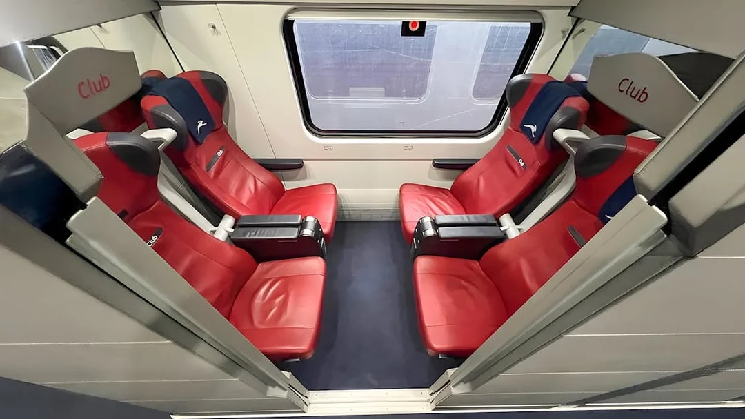 Italo train Club class seats with red upholstery and window view.