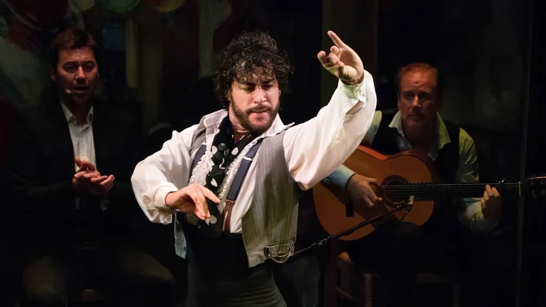 Flamenco dancer performing at Teatro Flamenco Triana with guitarist in background.