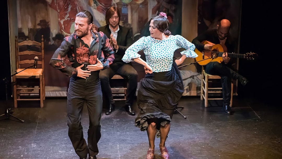 Flamenco dancers performing at Teatro Flamenco Triana with musicians in the background.