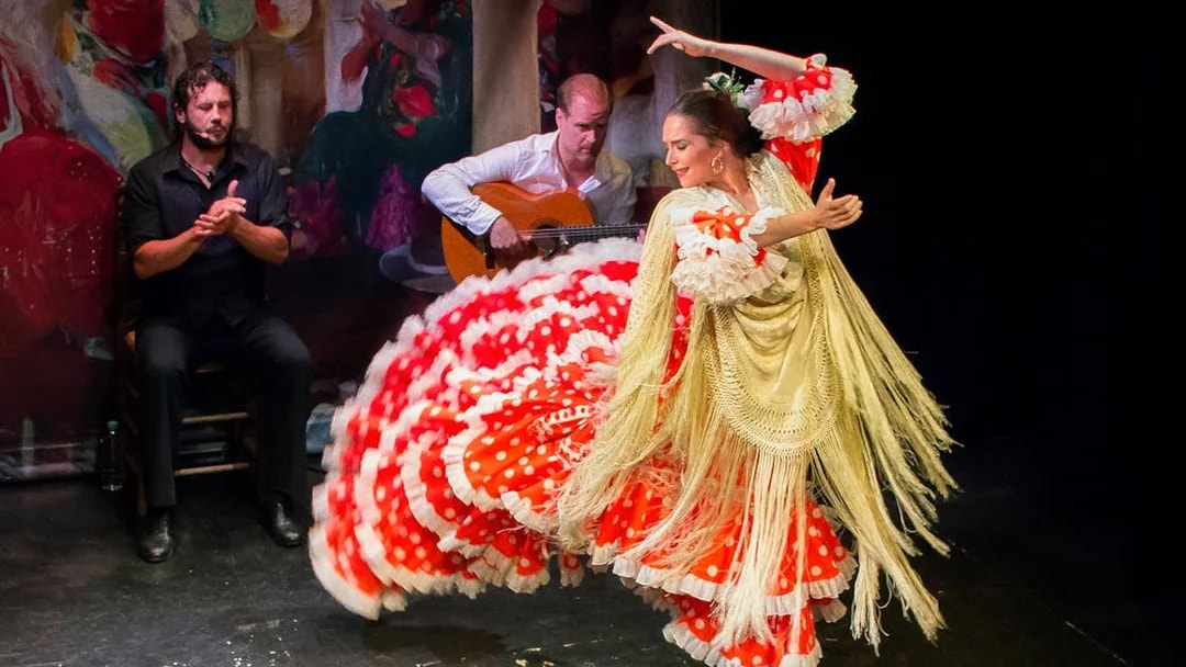 Flamenco dancer performing at Teatro Flamenco Triana with guitarist and singer.