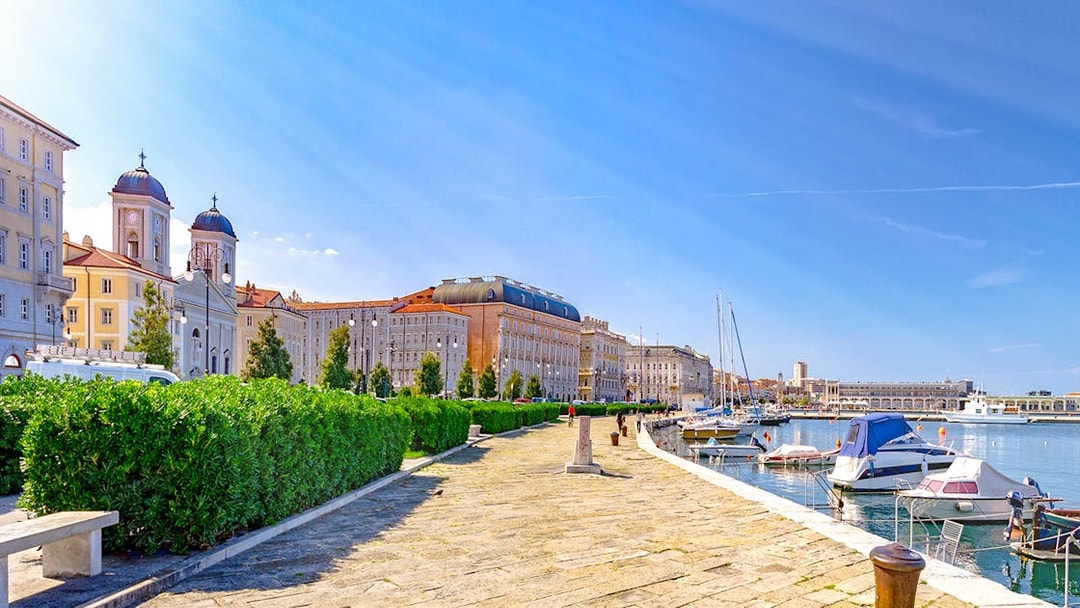 Trieste waterfront promenade with historic buildings and boats by the Adriatic Sea, Italy.