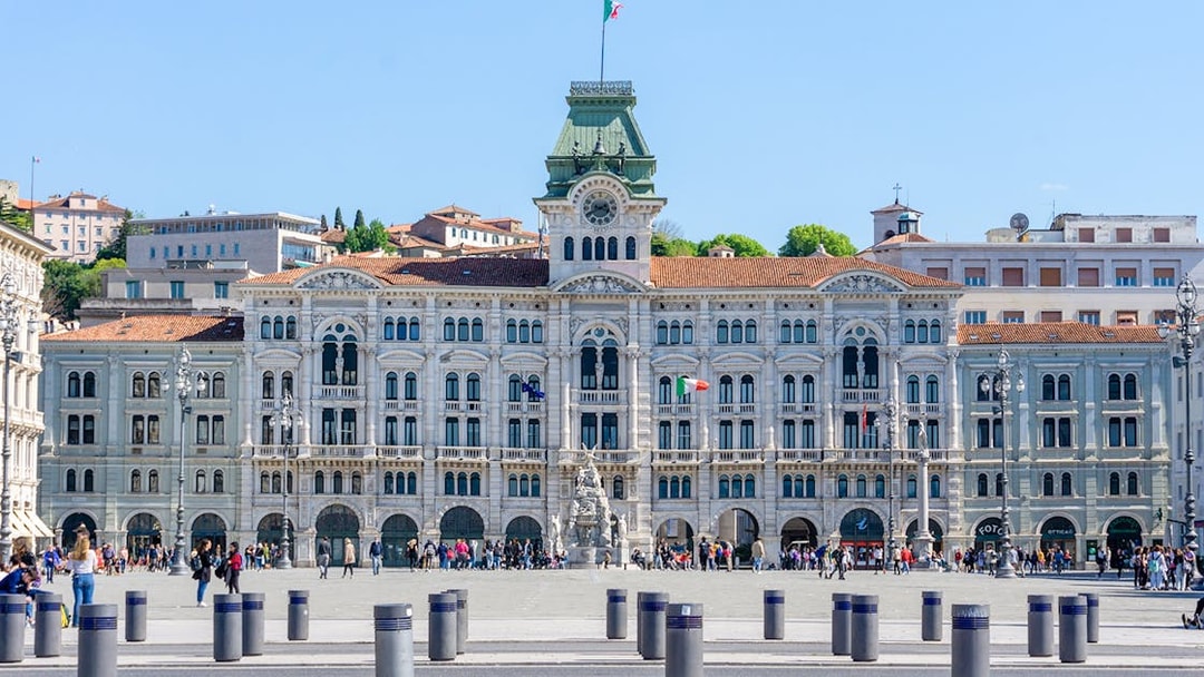 Piazza Unità d'Italia in Trieste with historic government building and people walking.