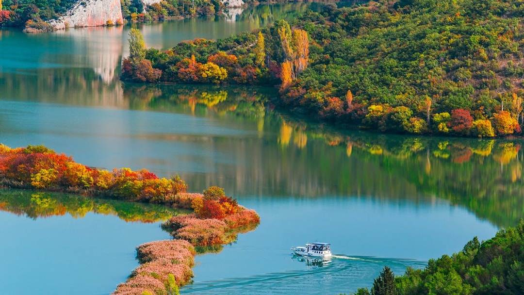 Boat cruising through Krka National Park's autumn landscape, Croatia.