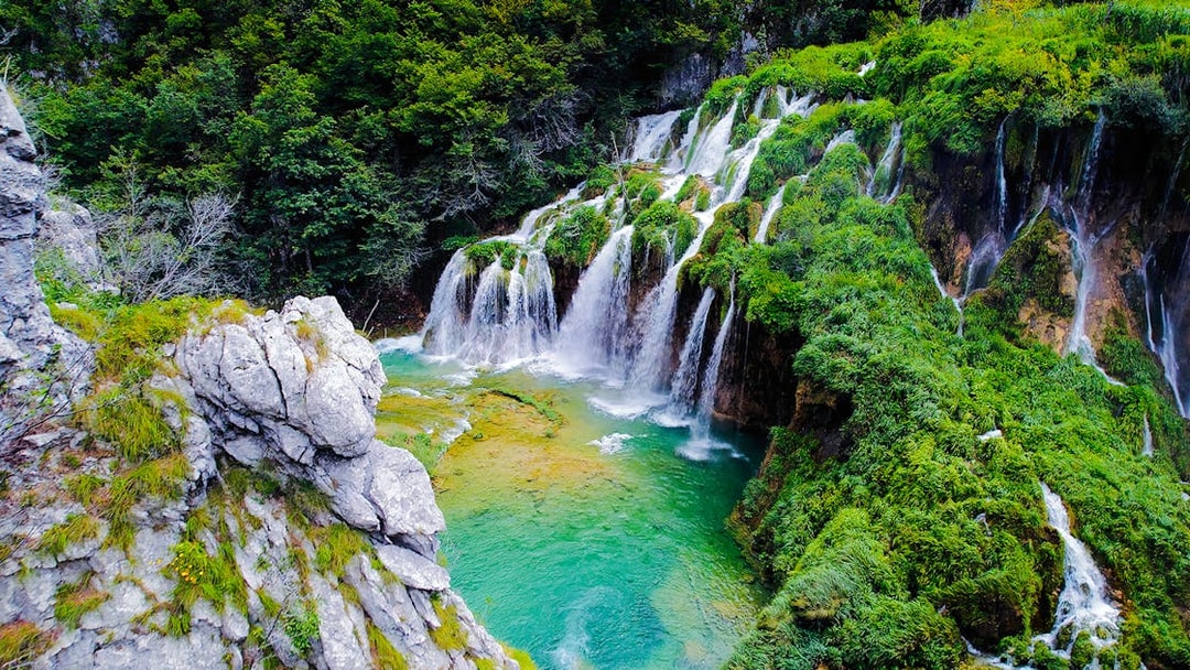 Waterfall cascading over lush greenery in Plitvice Lakes National Park, Croatia.
