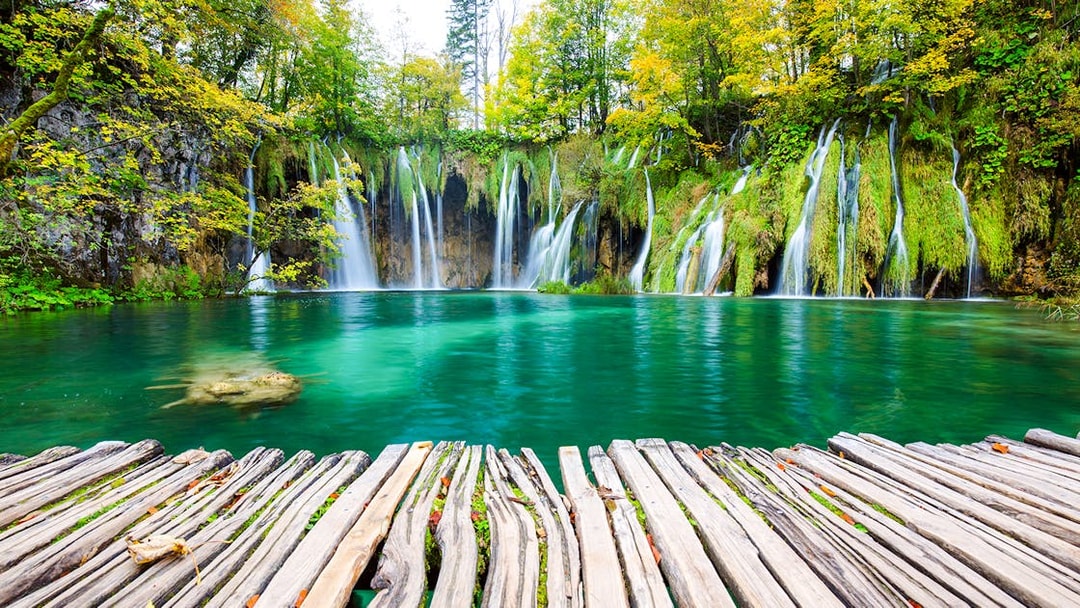 Waterfalls cascading into turquoise lake at Plitvice National Park, Croatia.