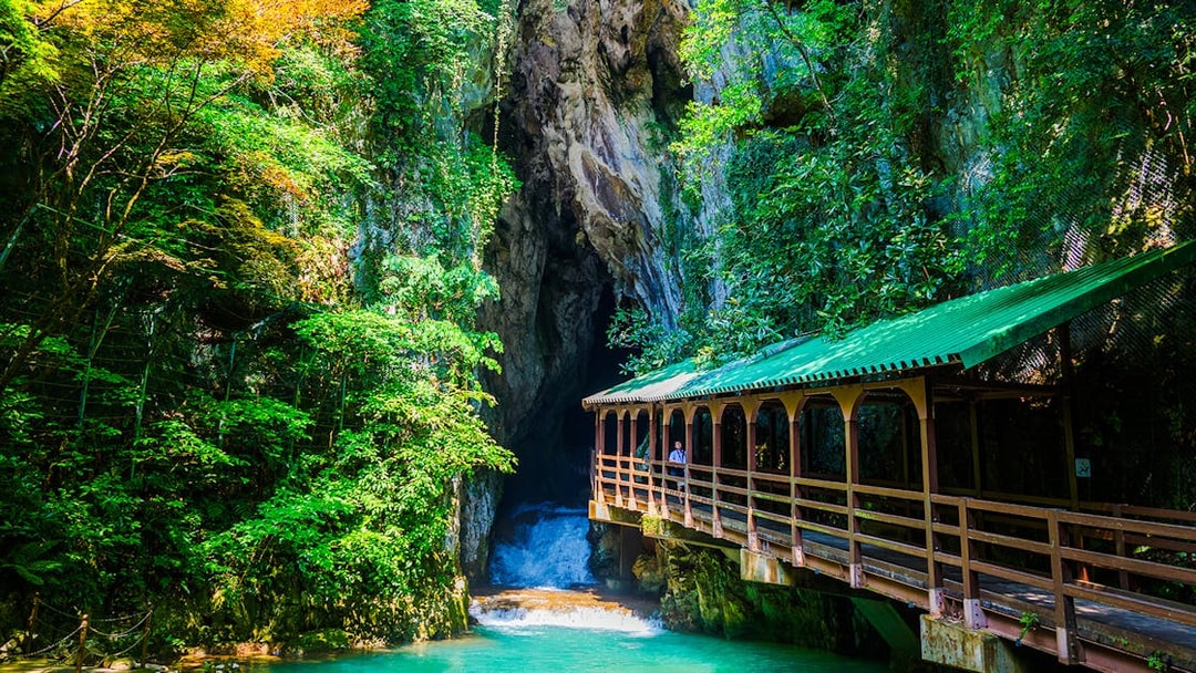 Entrance of a limestone cave with a wooden bridge, Plitvice Lakes National Park.