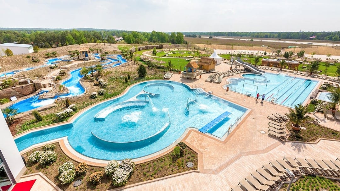 Outdoor pools and lazy river at Tropical Islands Resort, surrounded by greenery and lounge chairs.