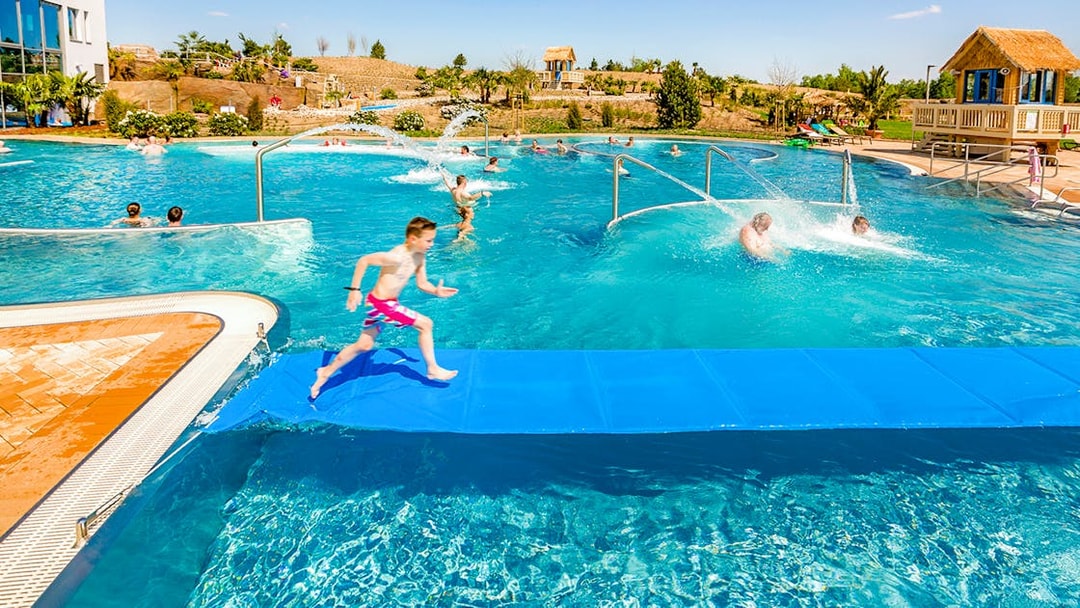Children playing in a pool at Tropical Islands Resort, featuring water slides and splash areas.