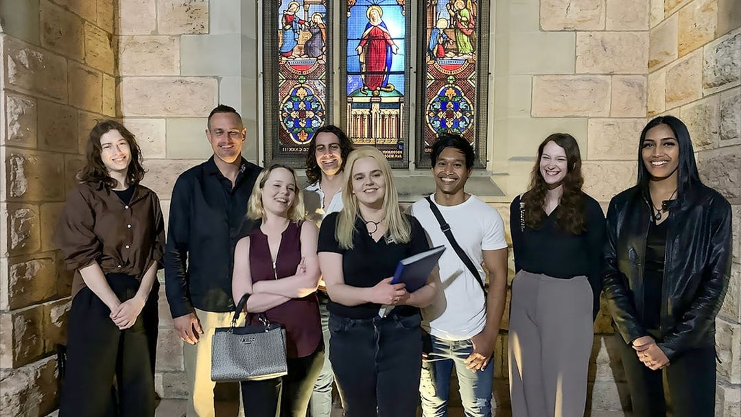 Group of people on Brisbane's True Crime Stories tour in front of a stained glass window.
