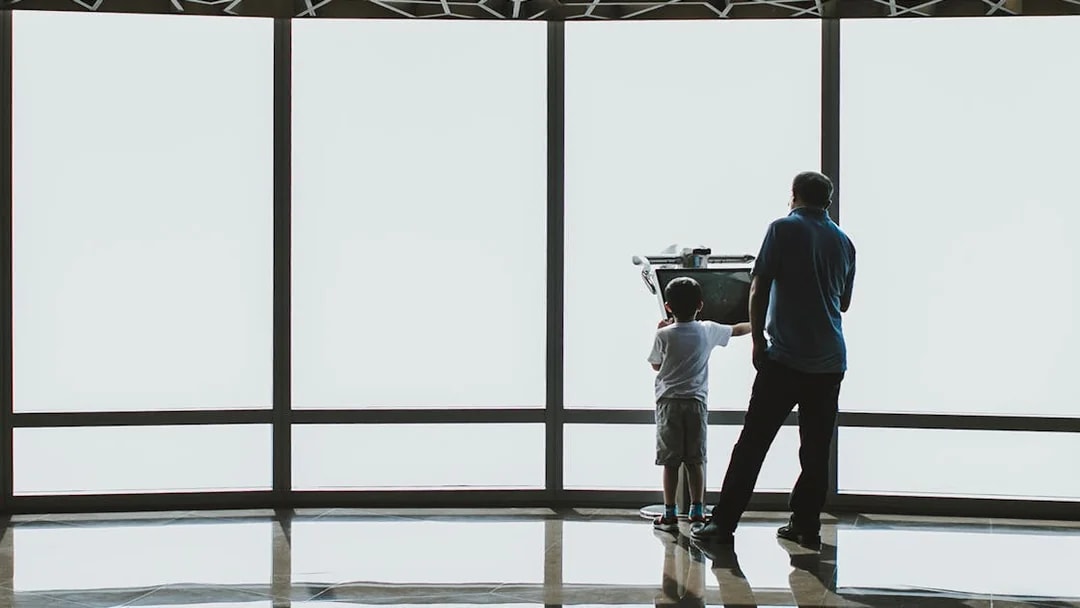 Child and adult using a telescope at Burj Khalifa observation deck, Dubai.