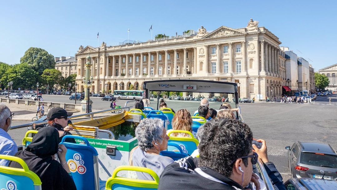 Tootbus tour passing Place de la Concorde in Paris, with passengers enjoying city views.