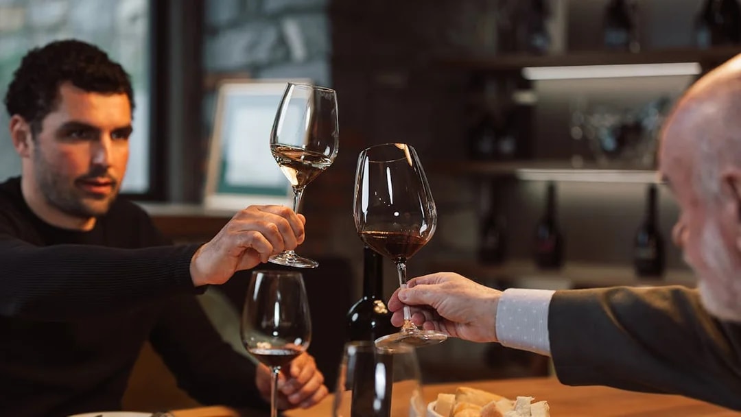 Wine tasting group toasting with glasses in a cozy cellar setting.