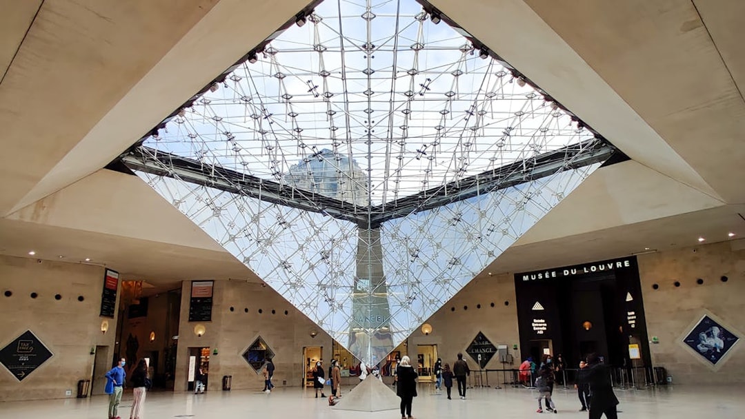 Inverted Pyramid inside Louvre Museum with visitors exploring the area.