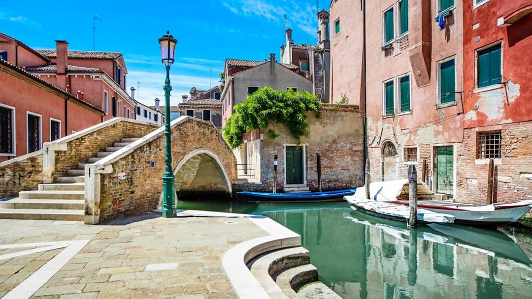 Venice canal with stone bridge and colorful buildings, part of Venice City Pass attractions.