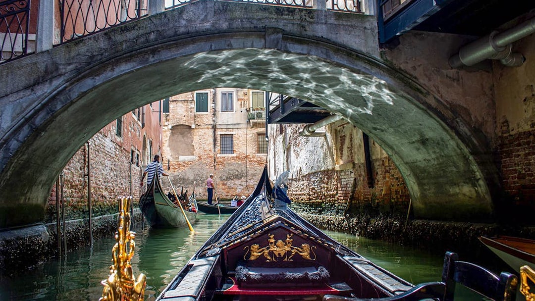 Gondola ride under a bridge in Venice, Italy, part of the Venice City Pass attractions.