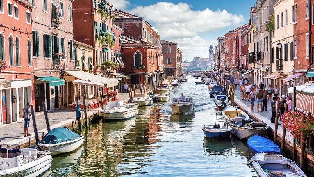 Venice canal with boats and colorful buildings, part of Venice City Pass attractions.