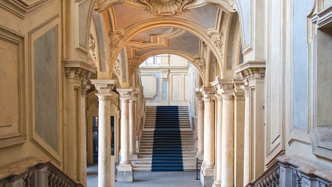 Grand staircase and ornate arches in a historic Turin palace, Italy.