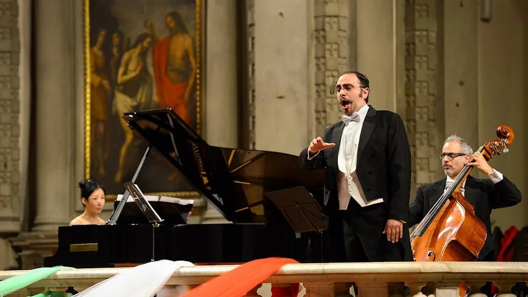Tenor performing with pianist and cellist at a concert in Florence.