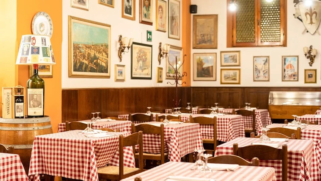 Tuscan restaurant with checkered tablecloths in Florence, Italy, set for dinner.