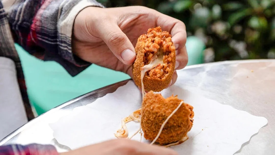 Person enjoying Suppli on a Rome food tour.