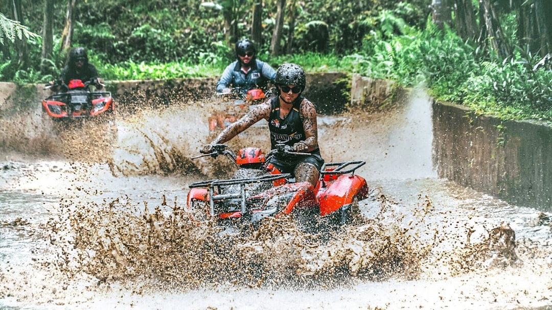 ATV riders splashing through mud in Ubud jungle adventure.